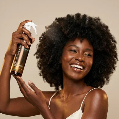Woman with a full afro holding Let It Grow spray