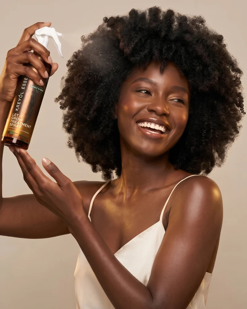 Woman with a coily afro spraying Let It Grow treatment spray
