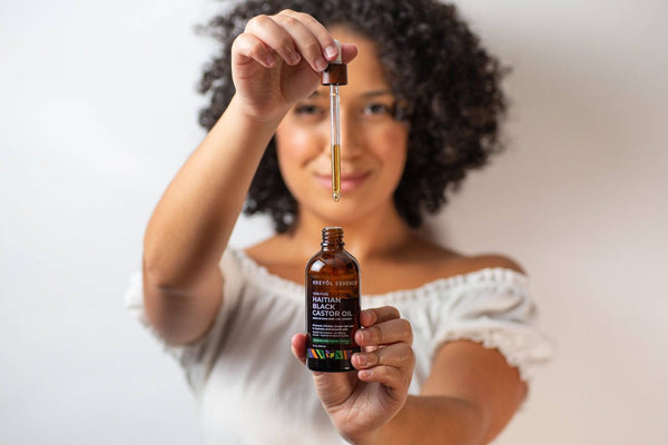 Haitian Black Castor Oil with rosemary and peppermint from Kreyòl Essence, shown in a clear glass bottle with label and natural ingredients.