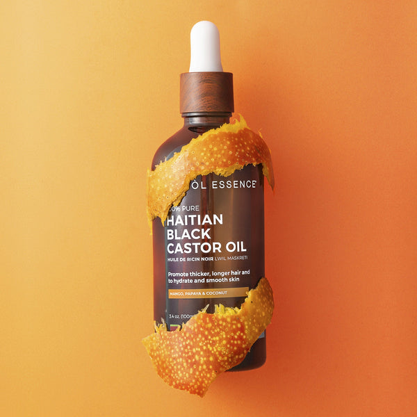 Haitian Black Castor Oil by Kreyòl Essence with mango, papaya, and coconut extracts in a clear bottle showing the product label.