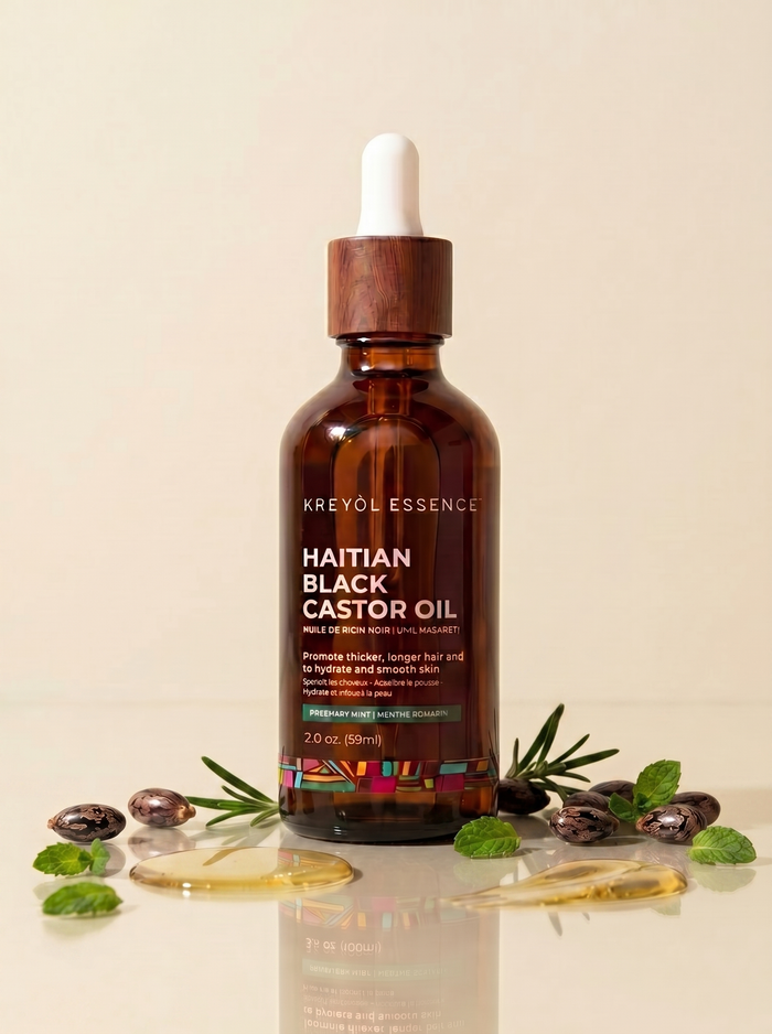 Kreyol Essence Haitian Black Castor Oil with rosemary and peppermint in a clear bottle, with the oil and herbal ingredients visible.